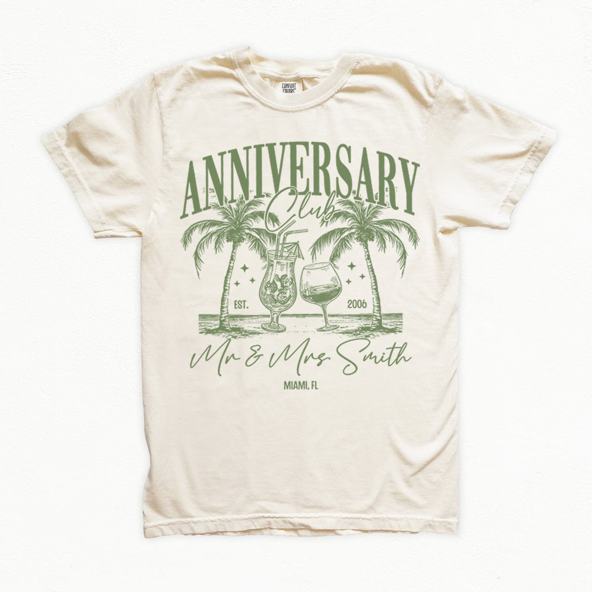 Beige bachelorette t-shirt with green 'Anniversary Club' design featuring palm trees and glasses on a white background.