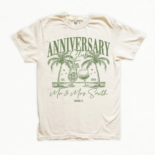 Beige bachelorette t-shirt with green 'Anniversary Club' design featuring palm trees and glasses on a white background.