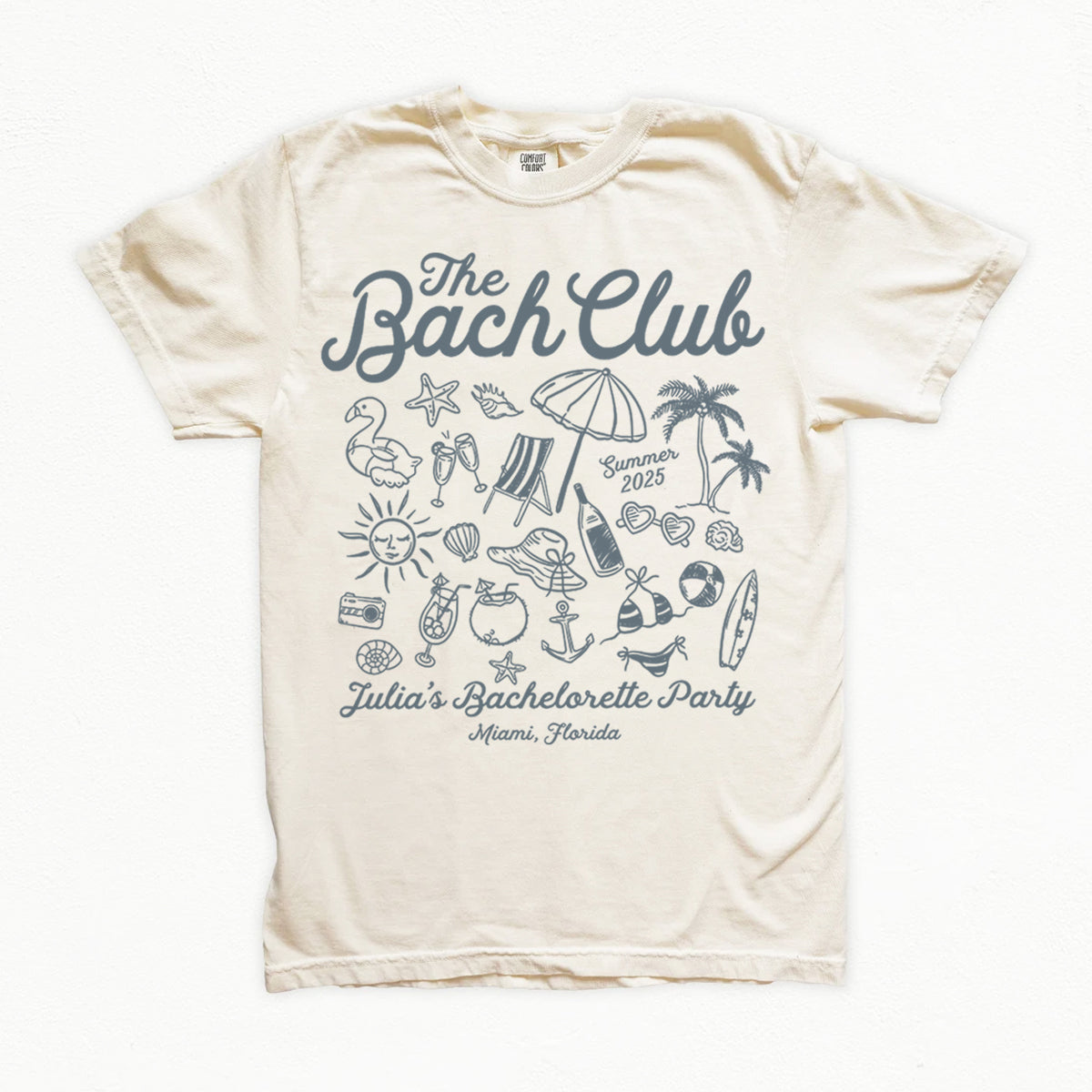 Beige bachelorette t-shirt with 'The Bach Club' design featuring beach-themed graphics on a white background.