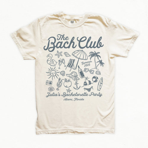Beige bachelorette t-shirt with 'The Bach Club' design featuring beach-themed graphics on a white background.