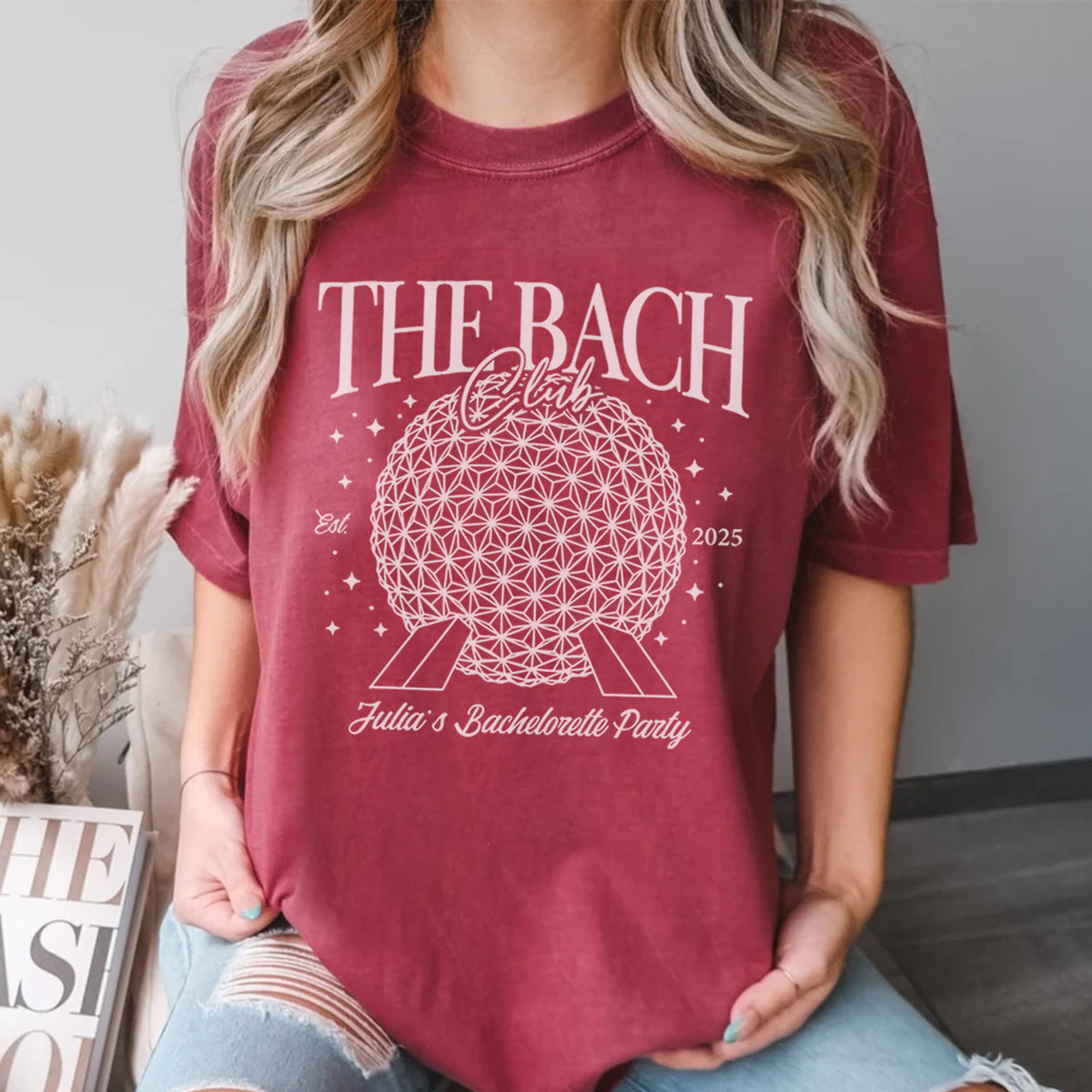 Person wearing a maroon bachelorette t-shirt with 'THE BACH' design and text.