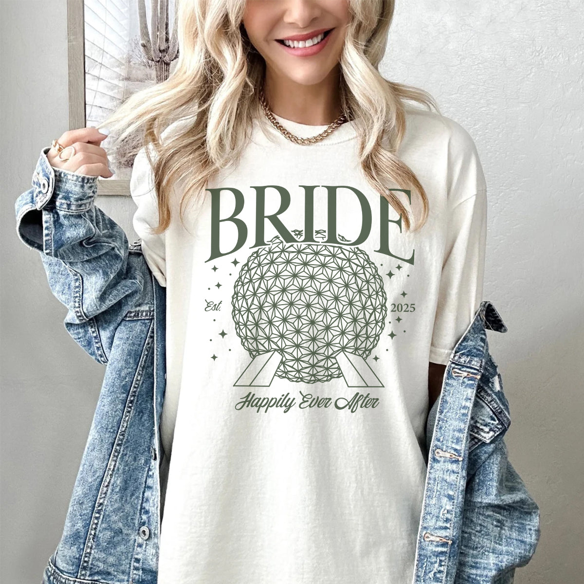Woman wearing a 'BRIDE' bachelorette t-shirt with a geometric design and text, holding a denim jacket.