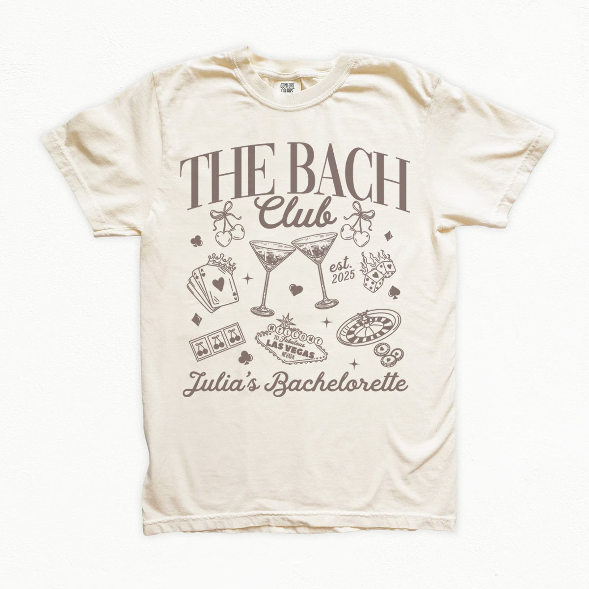 Beige bachelorette t-shirt with 'The Bach Club' and 'Julia's Bachelorette' text and graphics on a white background