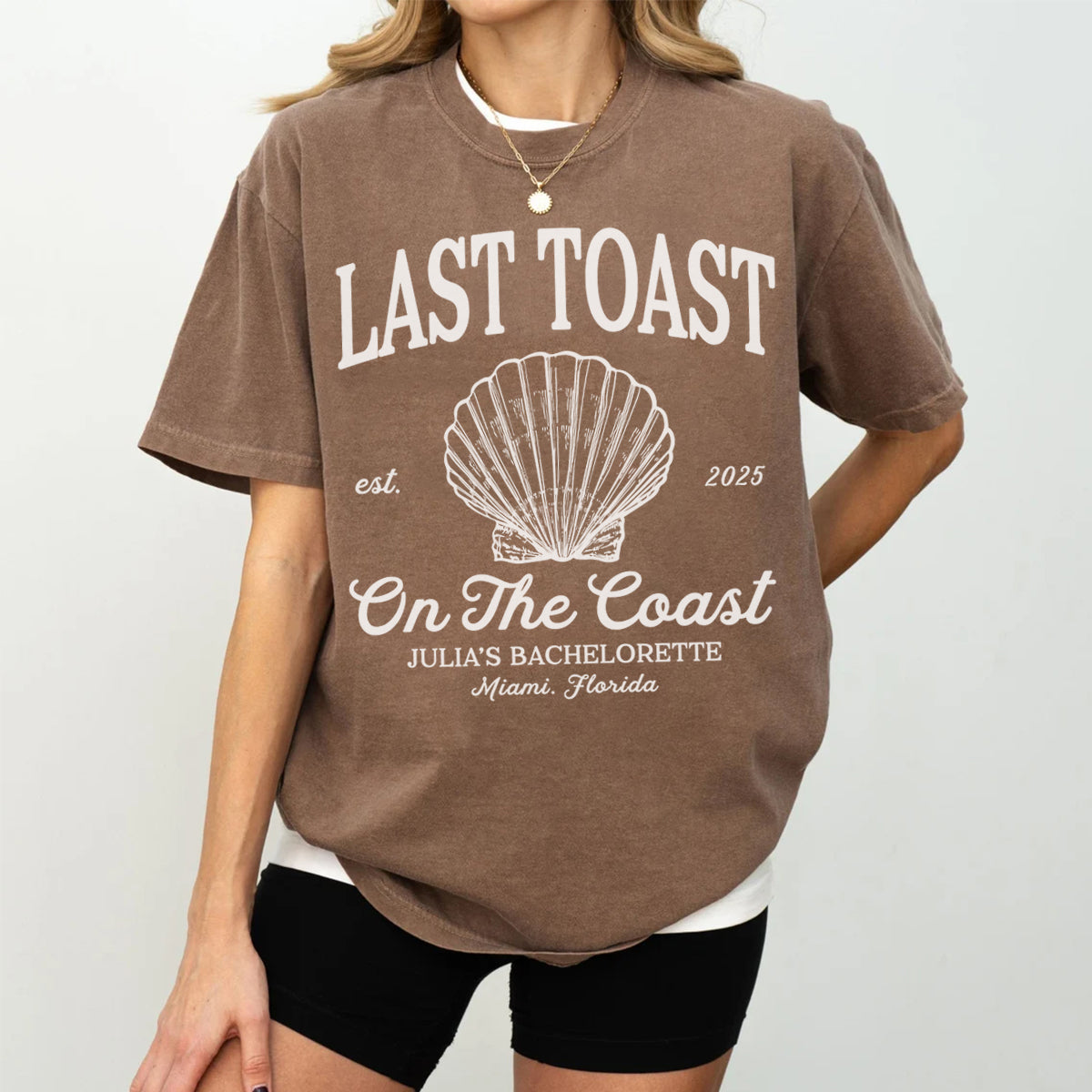 Person wearing a brown bachelorette t-shirt with 'Last Toast on the Coast' design.