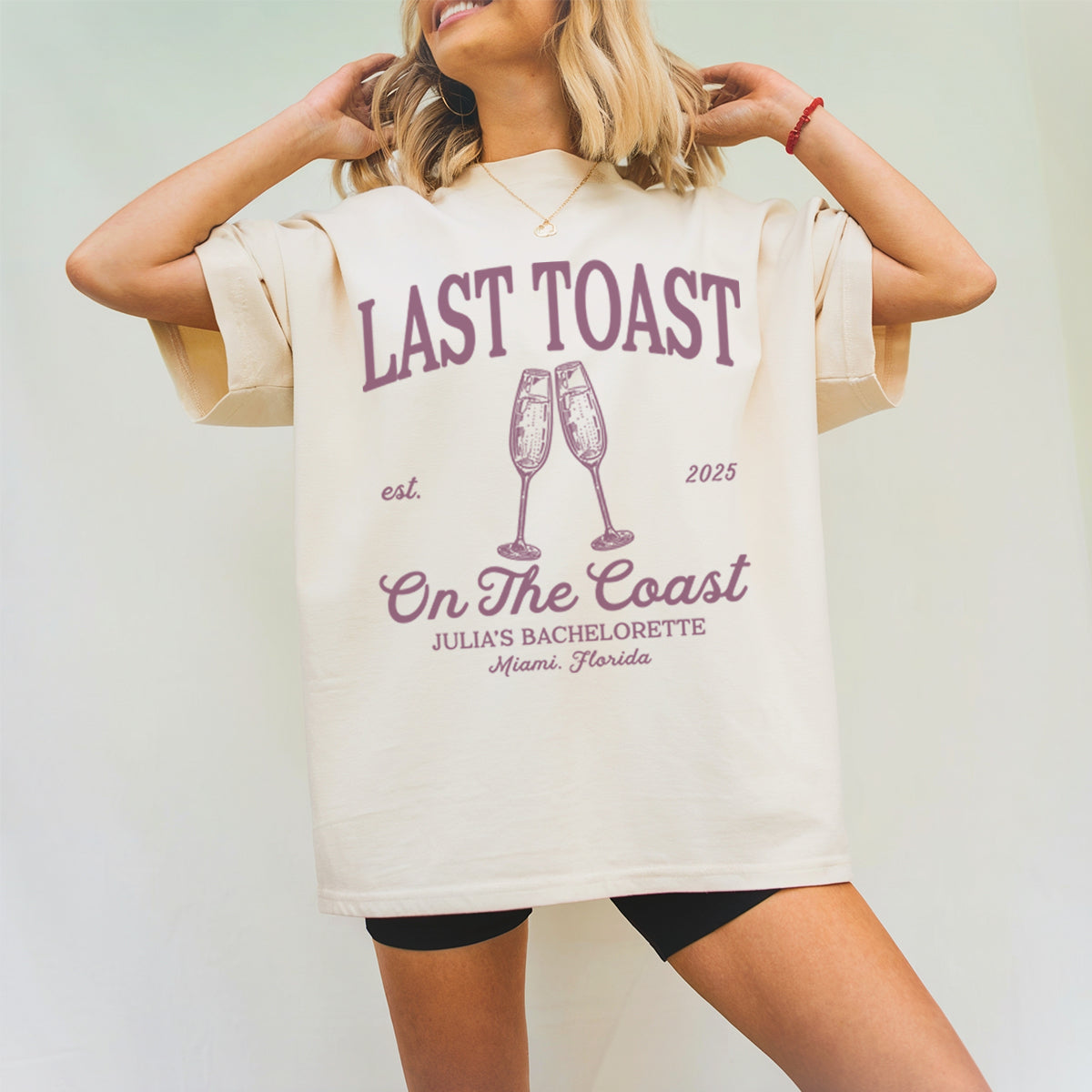 Person wearing a beige bachelorette t-shirt with 'Last Toast on the Coast' design.