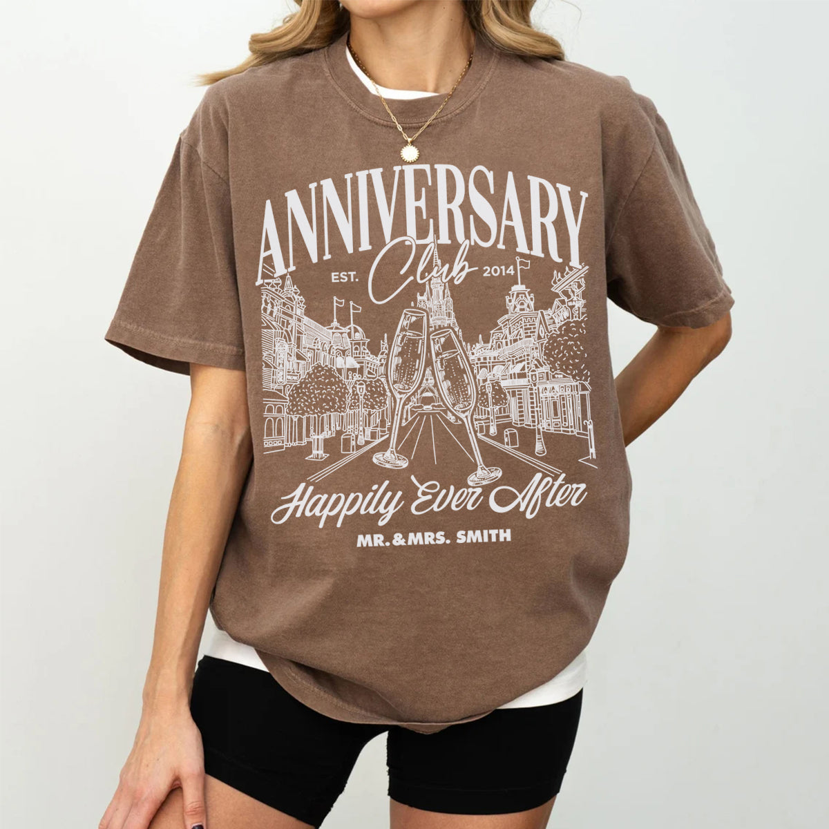 Person wearing a brown t-shirt with 'Anniversary Club' design on a plain background