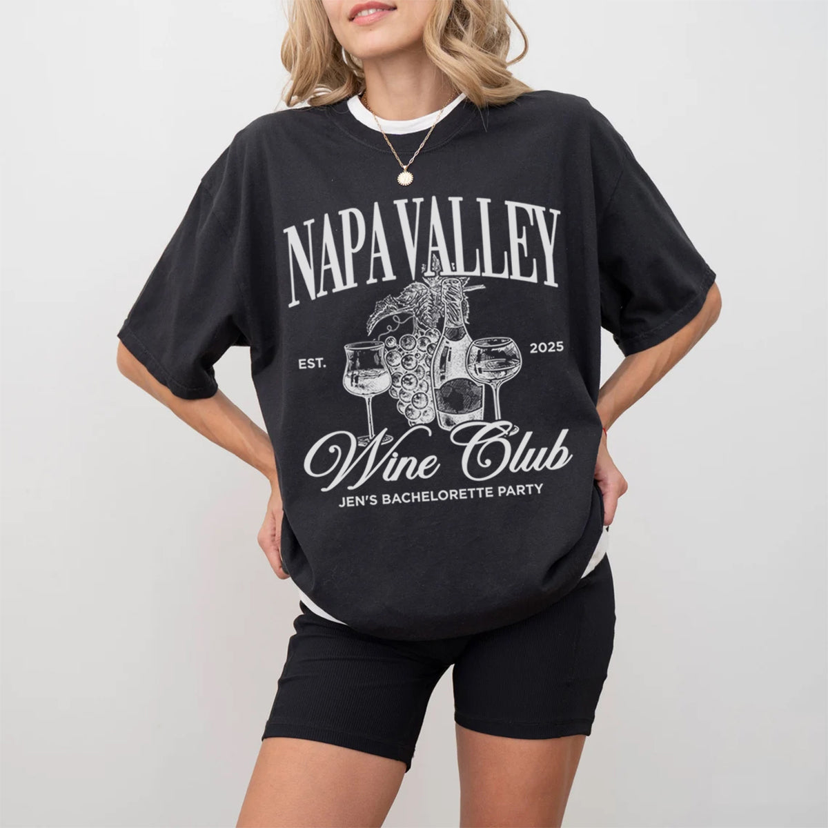 Person wearing a black oversized t-shirt with 'Napa Valley Wine Club' bachelorette design on a plain background
