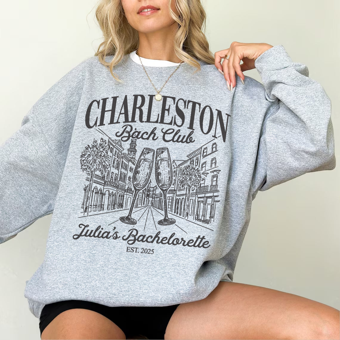 Person wearing a gray sweatshirt with 'Charleston Bachelorette Club' design.