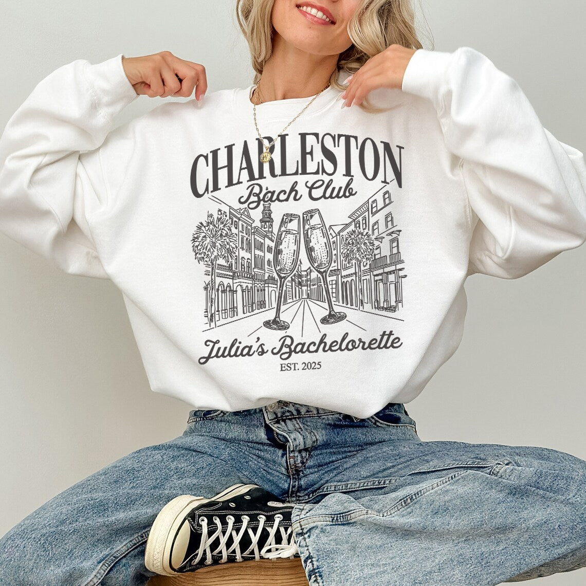 Person wearing a white sweatshirt with 'Charleston Bachelorette Club' design and text.
