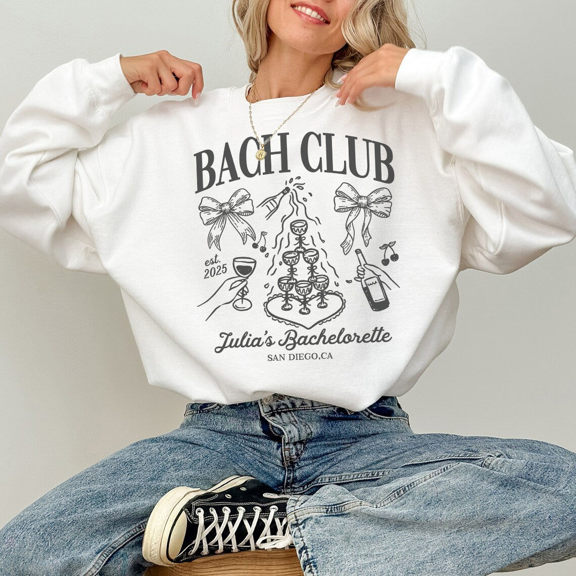 Person wearing a white sweatshirt with 'BACH CLUB' design and text.