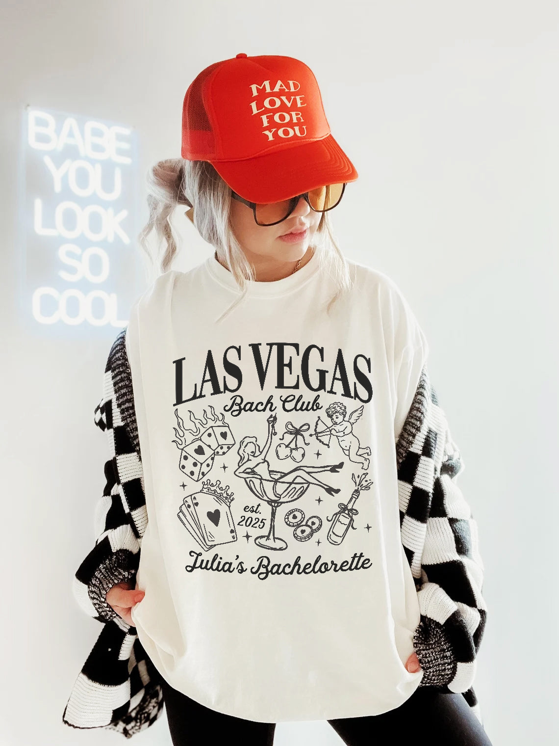 Person wearing a white sweatshirt with 'Las Vegas Bach Club' design and a red cap.